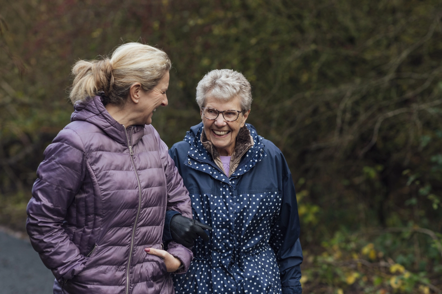 Stock photo showing a woman in her late middle age walking with an older woman.